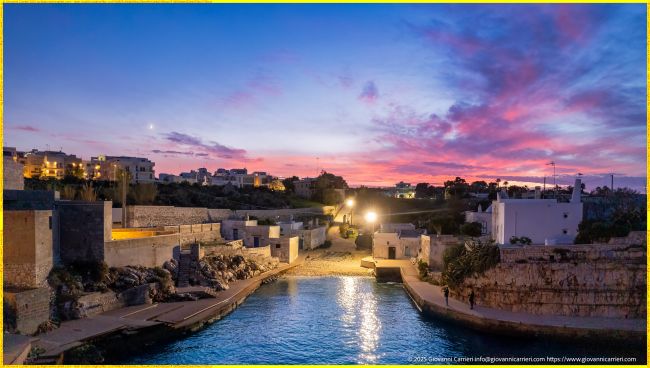 Veduta di Cala Paura al Calar della Sera, Con le Case del Borgo Illuminate a Polignano a Mare, Puglia