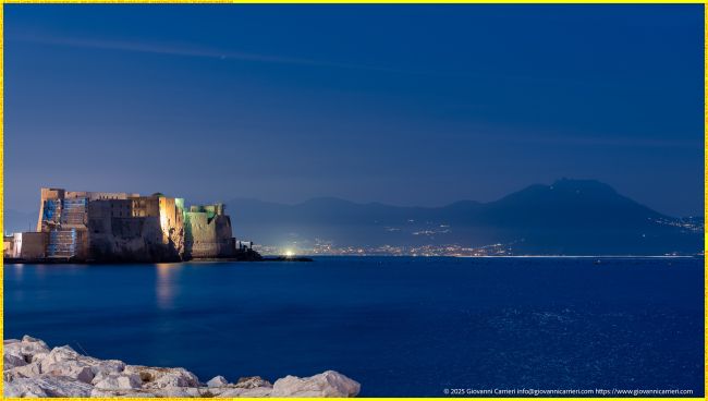 Fortezza Castel dell'Ovo illuminata e Monte Vesuvio in silhouette a Napoli