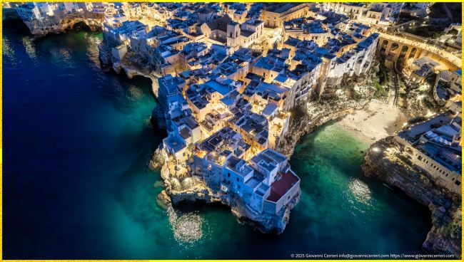 Visione Aerea Esclusiva del Centro Storico di Polignano a Mare e dell'Iconica Lama Monachile Illuminati di Notte